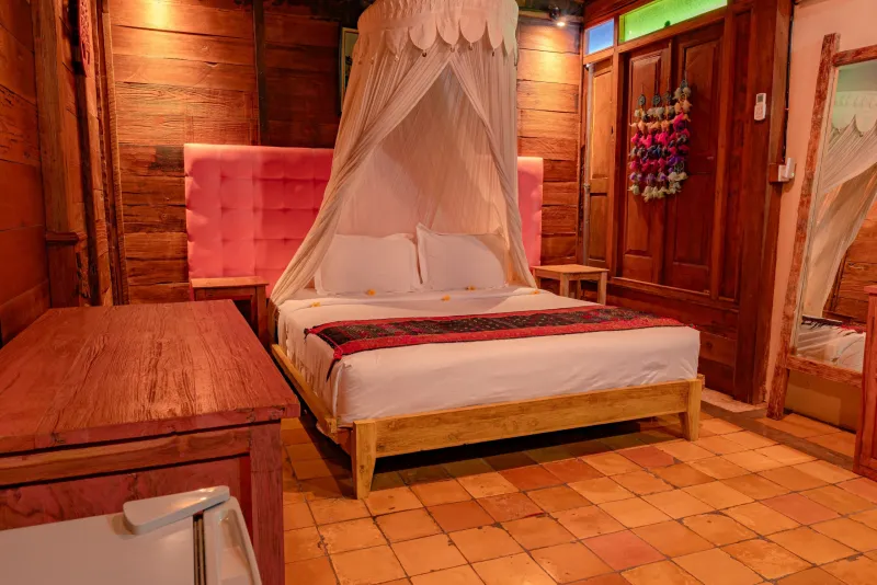 Rustic room with pink headboard and terracotta floor