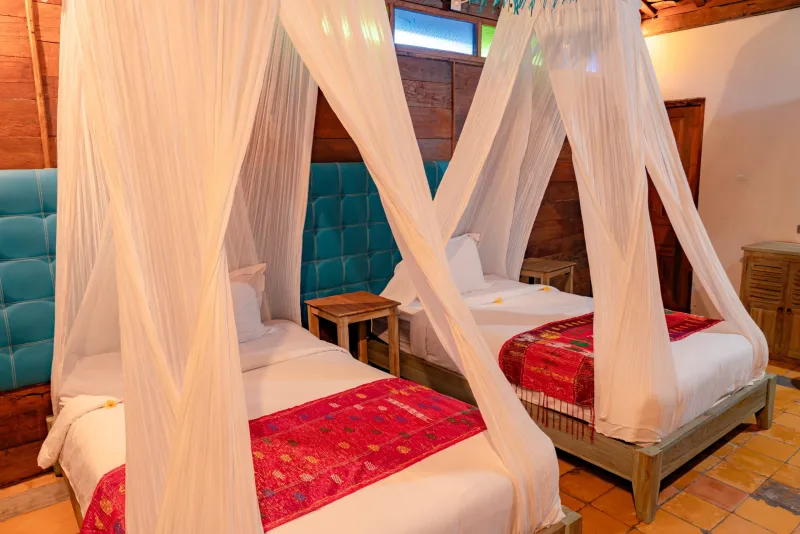 Tempat tidur kembar dengan kepala tempat tidur teal dan kelambu